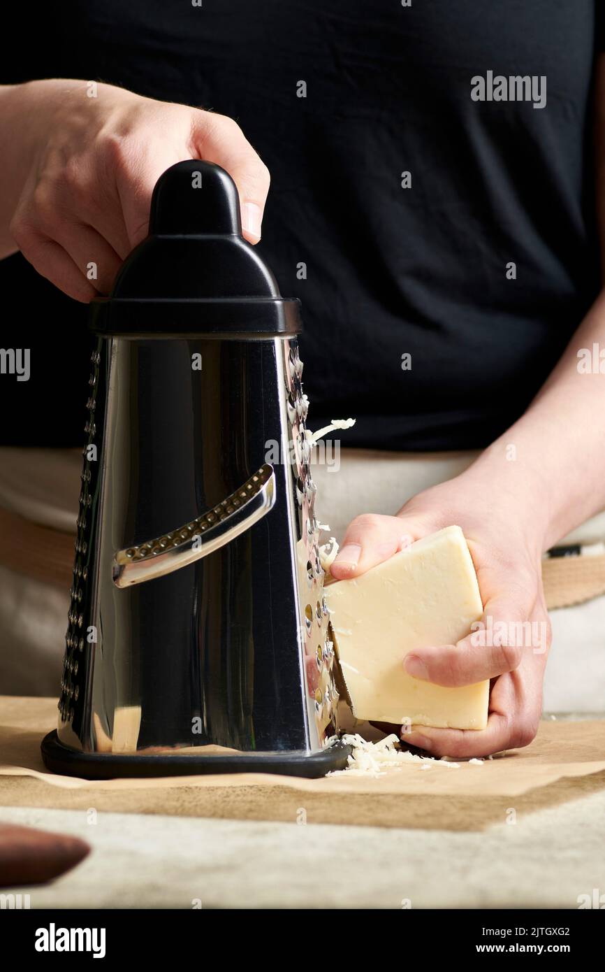 Hands grating cheese onto parchment paper Stock Photo Alamy