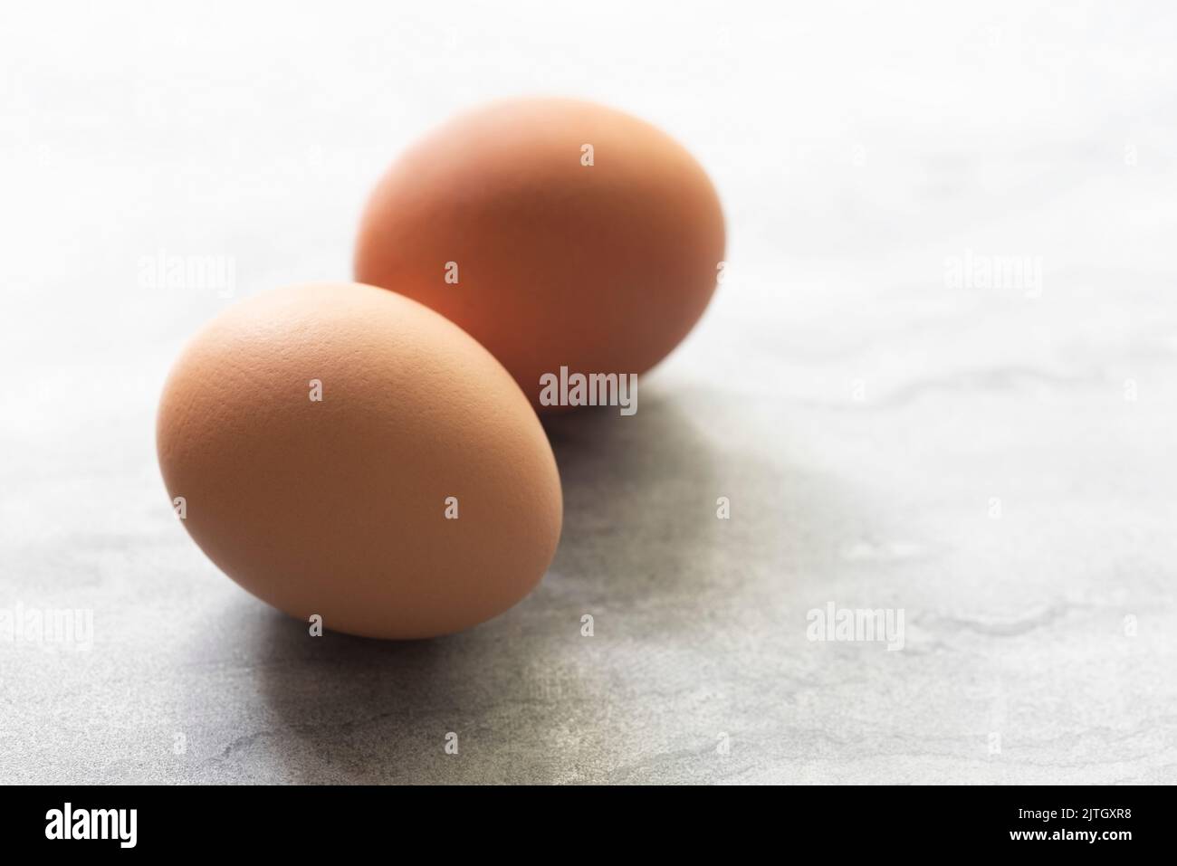 Two whole chicken eggs on a textured white background Stock Photo Alamy