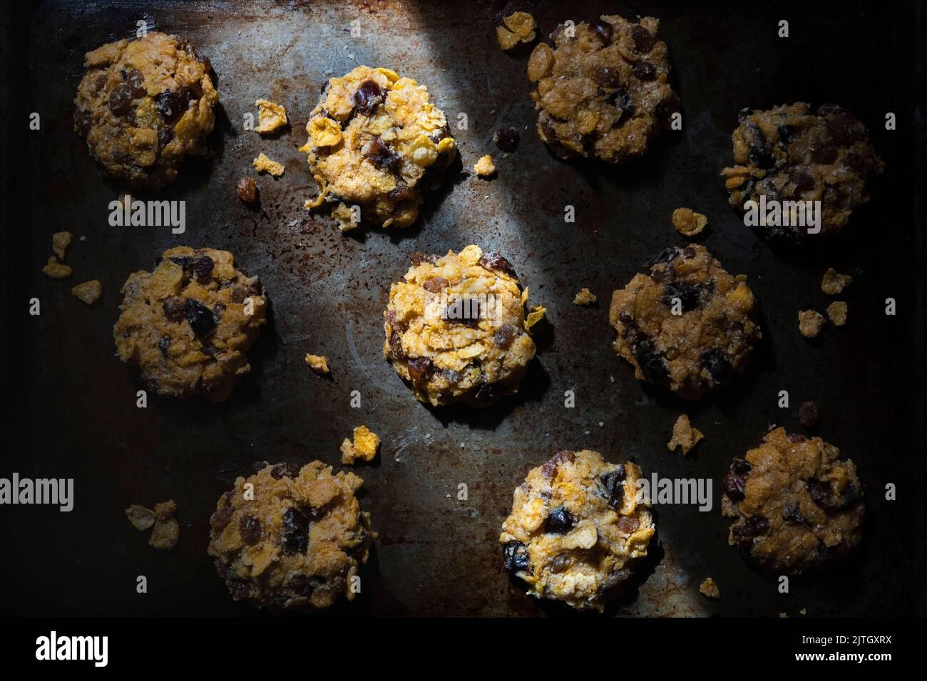 Corn flake and date cookies on a baking tray in light and shadow. Stock Photo