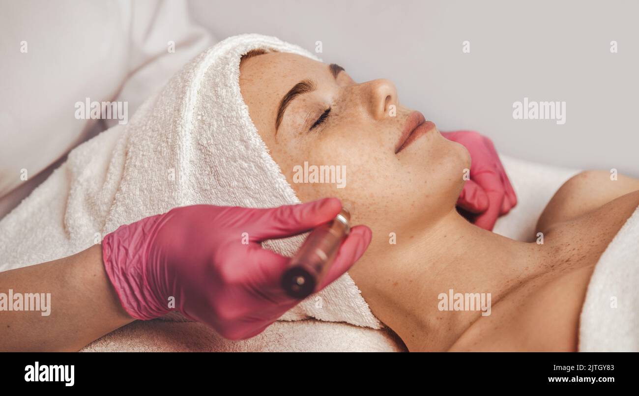 Professional beautician using derma pen on woman's face skin, at spa ...