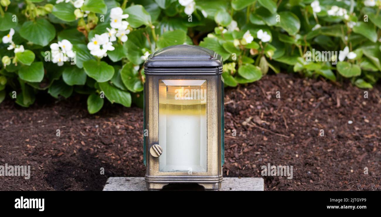 brass grave light with burning candle on a grave Stock Photo