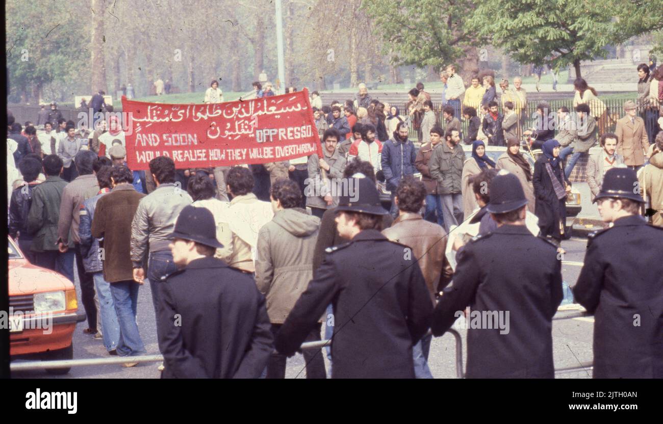 April 30, 1980, London, United Kingdom: Iranian supporters carrying a large protest banner march in London during the six-day siege of the Iranian Embassy. From 30 April to 5 May 1980, a group of six armed Iranian dissidents, opposed to Ayatollah Khomeini, the religious leader who came to power in 1979, took over the Iranian embassy on Prince's Gate in South Kensington, London. The Iranian group took 21 hostages two of whom were killed. Near to the scene of the siege, supporters of Khomeini made their views known with a protest. The dramatic six-day siege ended when elite British SAS troops st Stock Photo