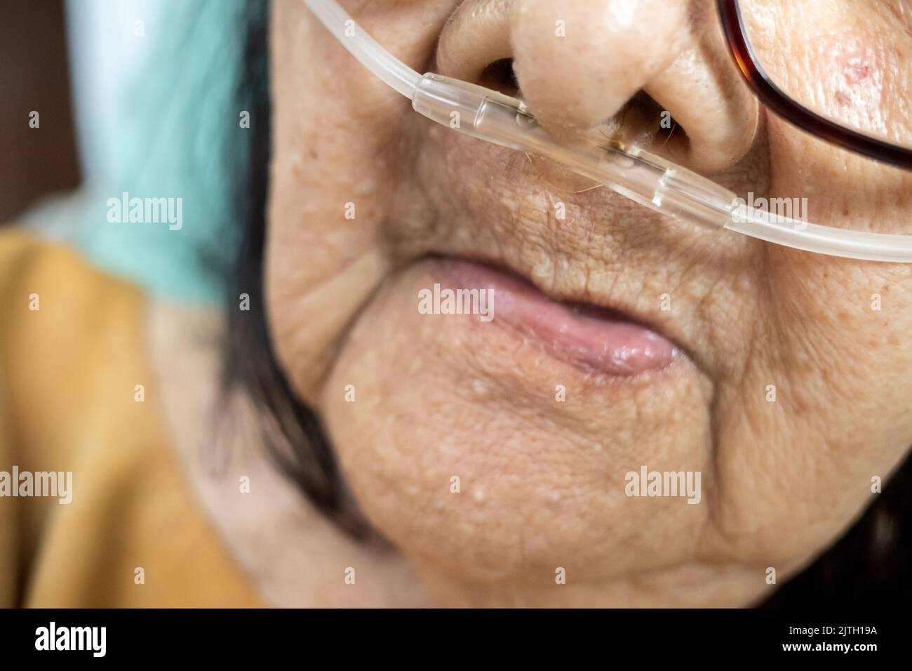 Closeup face of sick Southeast Asian female senior patient with respiratory disorders bedrest in hospital Stock Photo