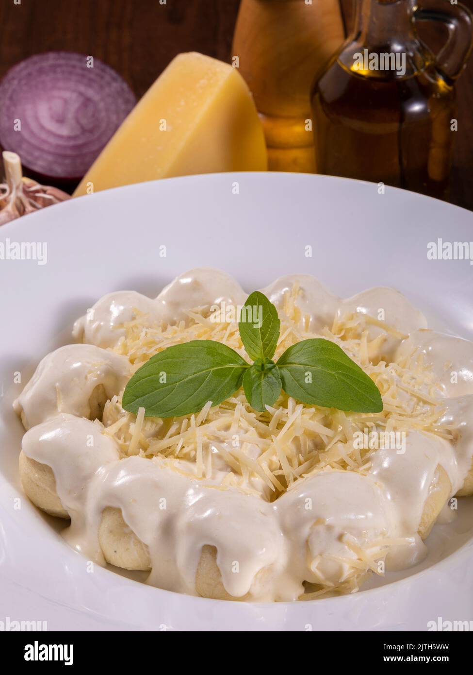Potato gnocchi in white sauce with grated Parmesan cheese and basil