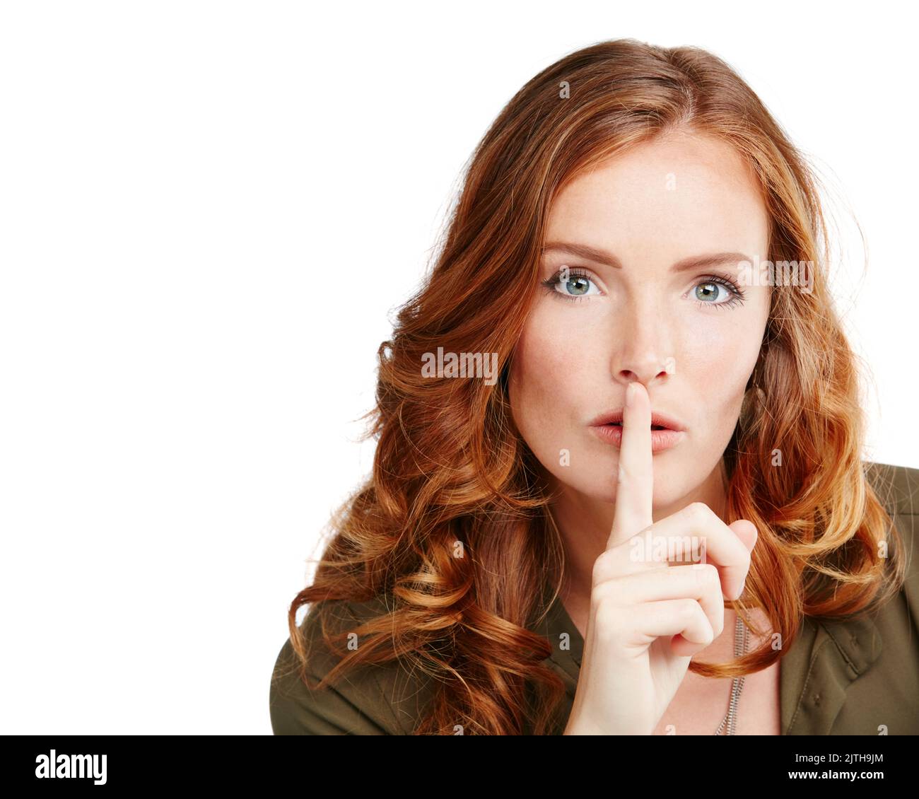 I hope you can keep a secret. Studio shot of a young woman posing with her finger on her lips. Stock Photo