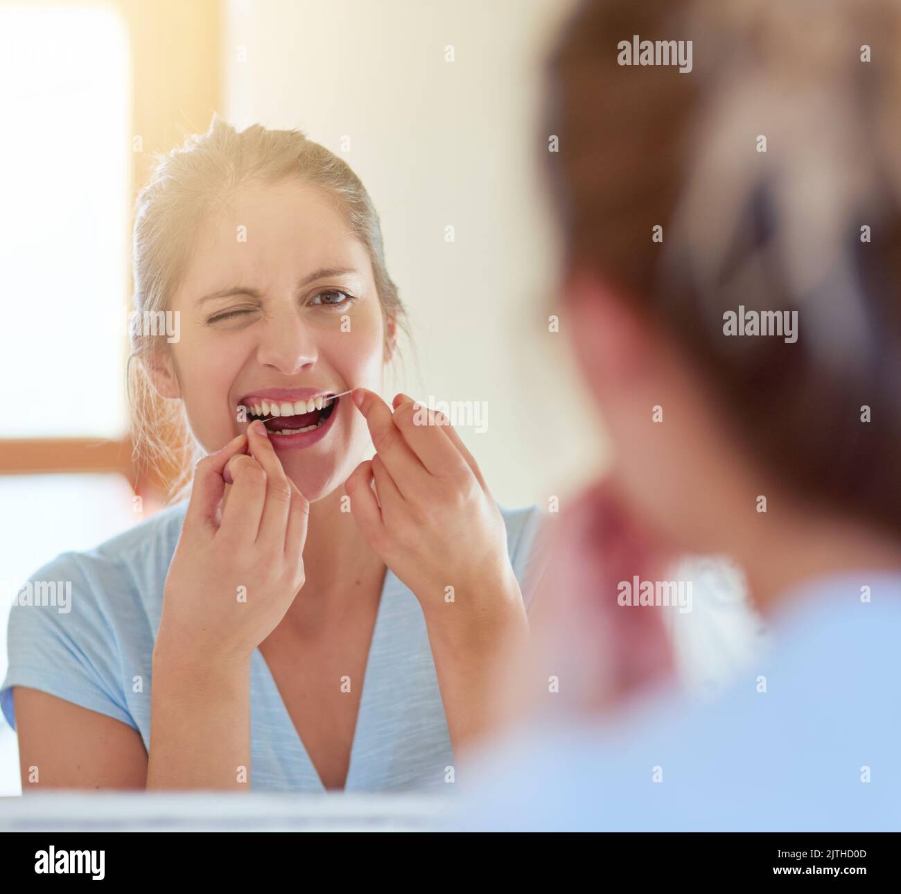 Cleaning all those hard to reach places. a young woman flossing her