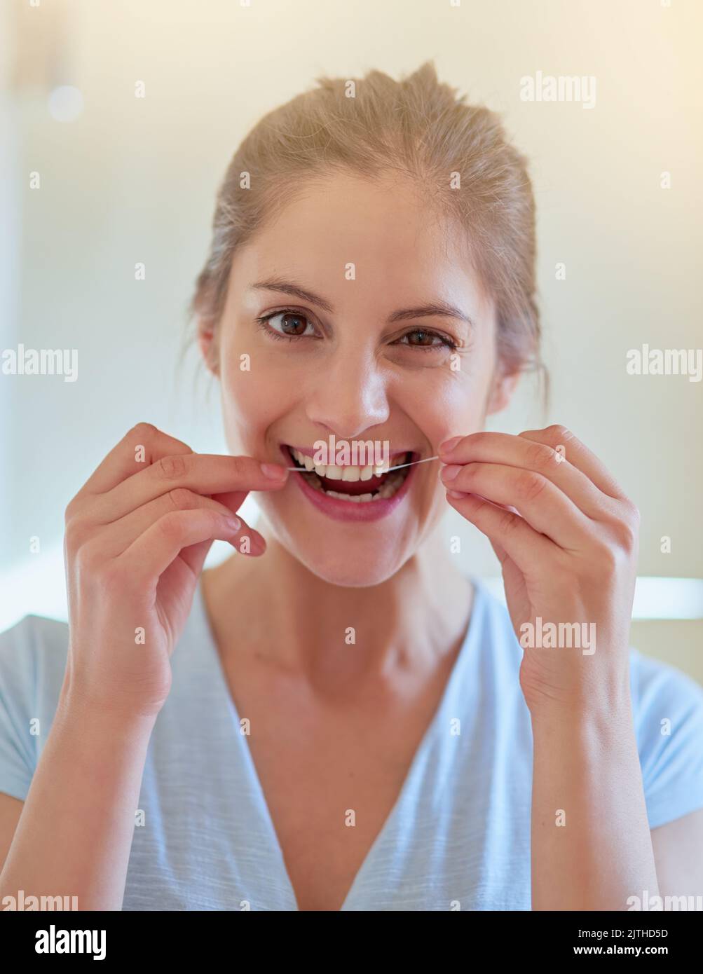 Maintaining Her Perfect And Pearly Smile Portrait Of A Young Woman Flossing Her Teeth In A 