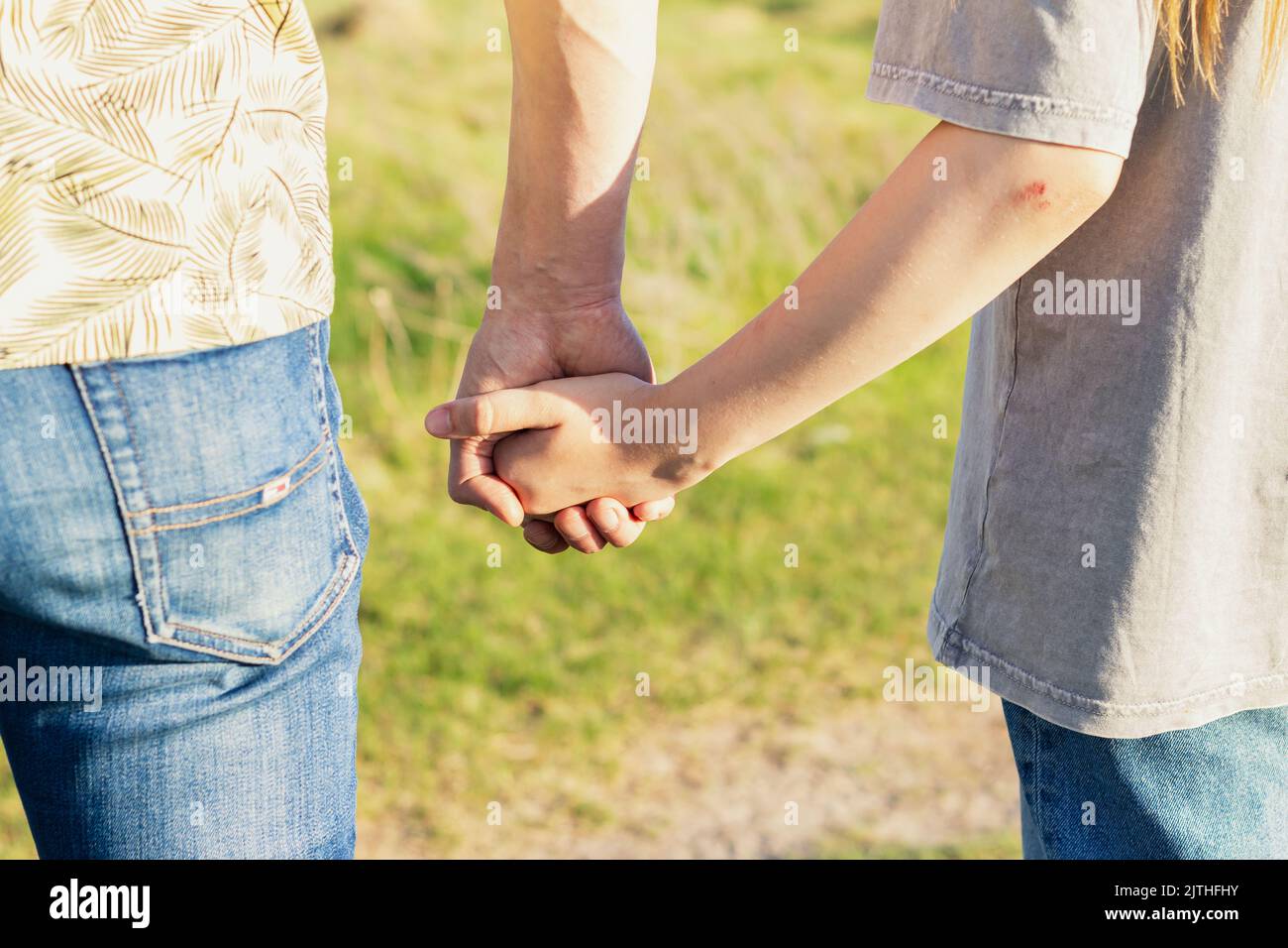 Father holds daughter's hand on blurred nature background, outdoor. Back of Father and daughter hands. Trust, care and parenting family, father's day Stock Photo