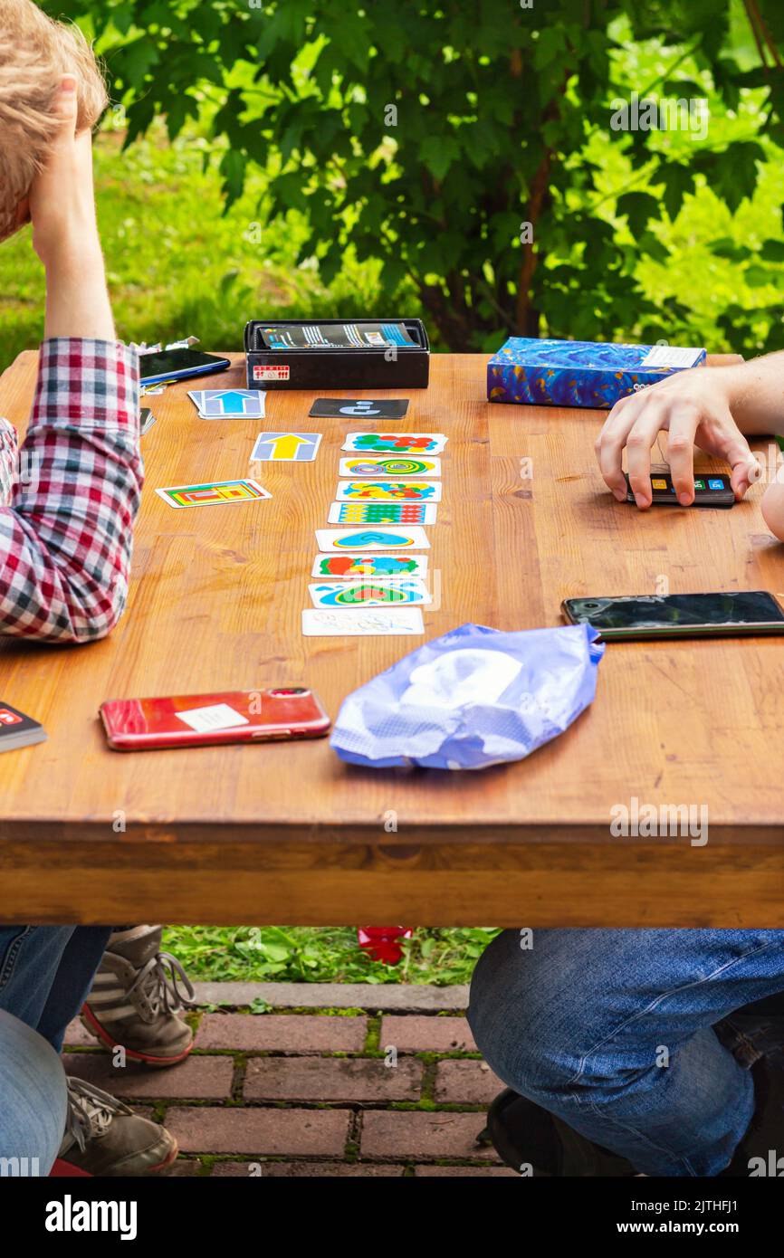 Close-up, hands of father and son playing board games on cozy terrace of country house on wooden table against blurred greenery. Friendship Day, Fathe Stock Photo