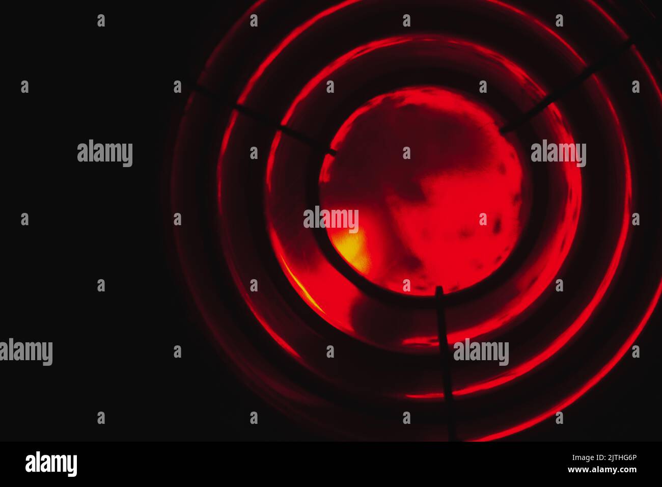 Red lighthouse light glows in the dark behind a Fresnel lens. Abstract