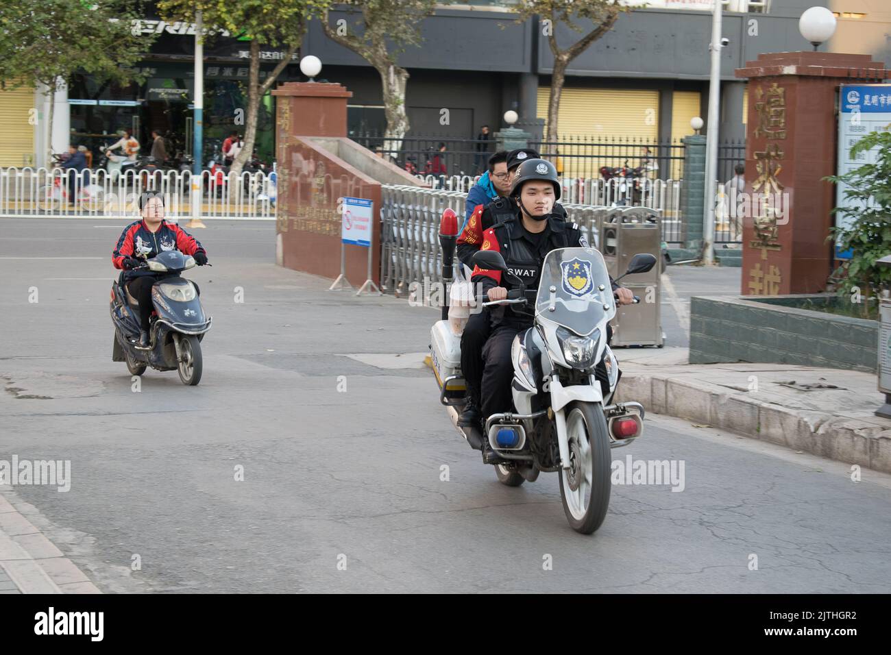 People ride electric scooters and Chinese SWAT cops riding a motorbike in Kunming Stock Photo