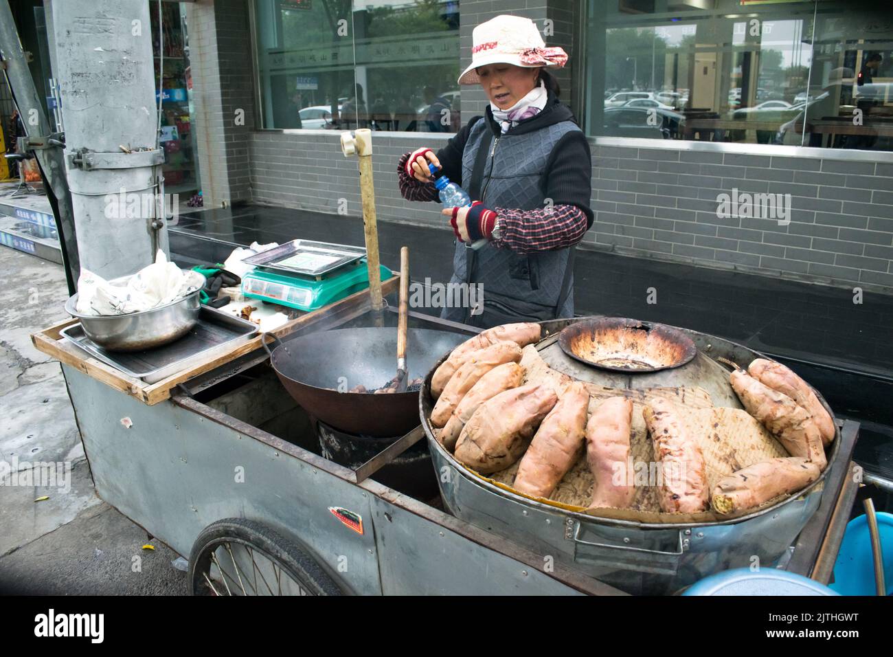 Street food, roasted Sweet Potatoes and Chestnuts roasted in a wok sold by a Chinese vendor. Stock Photo