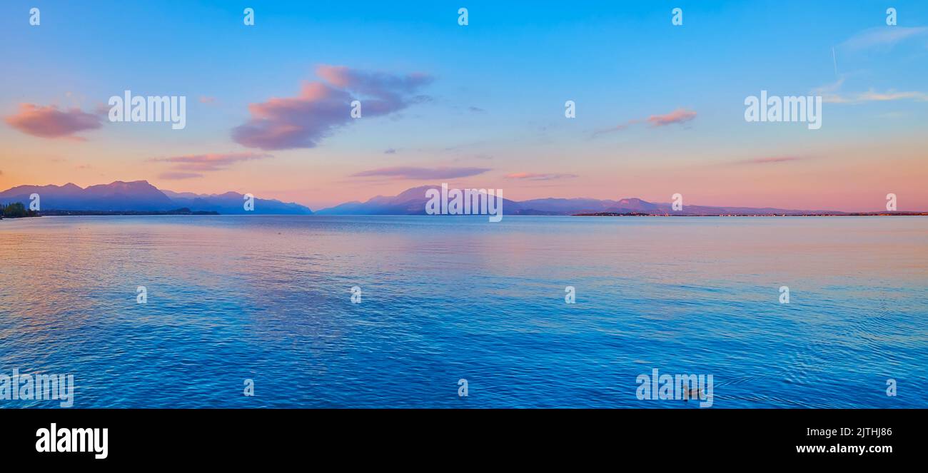 The picturesque foggy purple sunset over the Lake Garda and Garda Prealps, Desenzano del Garda, Italy Stock Photo