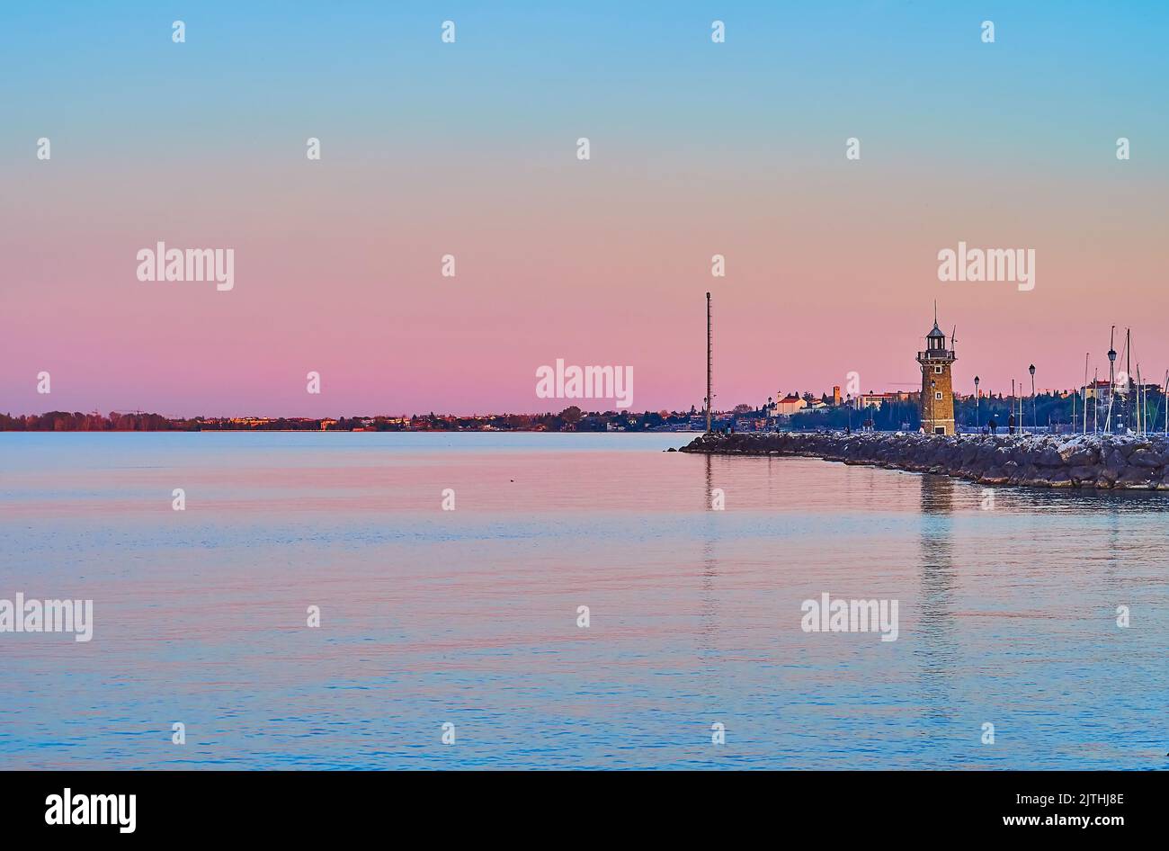 The bright purple dusk on Lake Garda with a view on the old stone lighthouse at the entry of the Porto Vecchio (Old Port), Desenzano del Garda, Italy Stock Photo