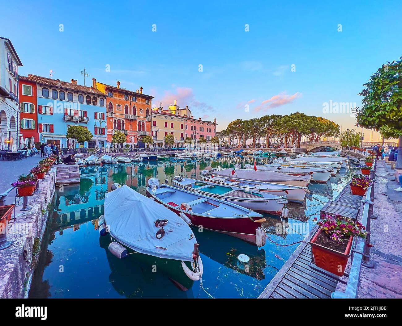 The beautiful sunset in Old Port (Porto Vecchio) with a view on fishing boats in a tiny marina and line of historic townhouses, lighted in purple colo Stock Photo