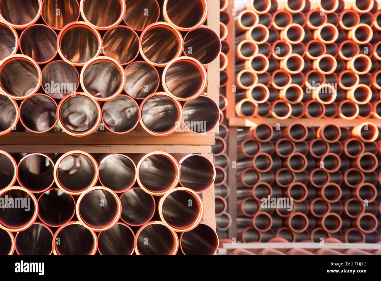 Background of orange plastic sewage pipes used at the building site. Texture and pattern of plastic drainage pipe. Light through tubes. Stock Photo