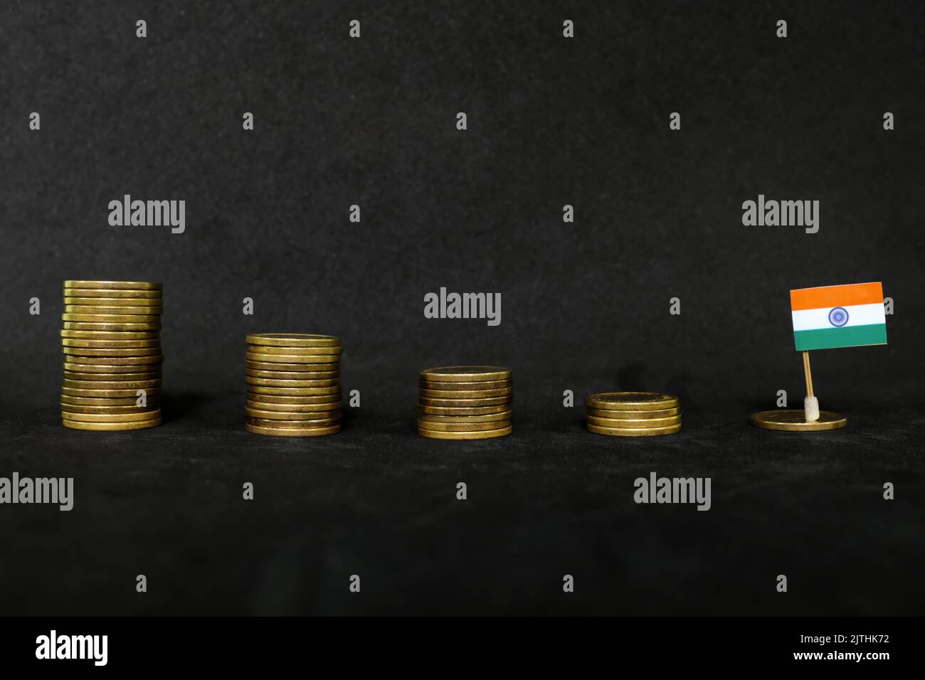 India economic recession, financial crisis and peso depreciation concept. Indian flag in decreasing stack of coins in dark black background. Stock Photo
