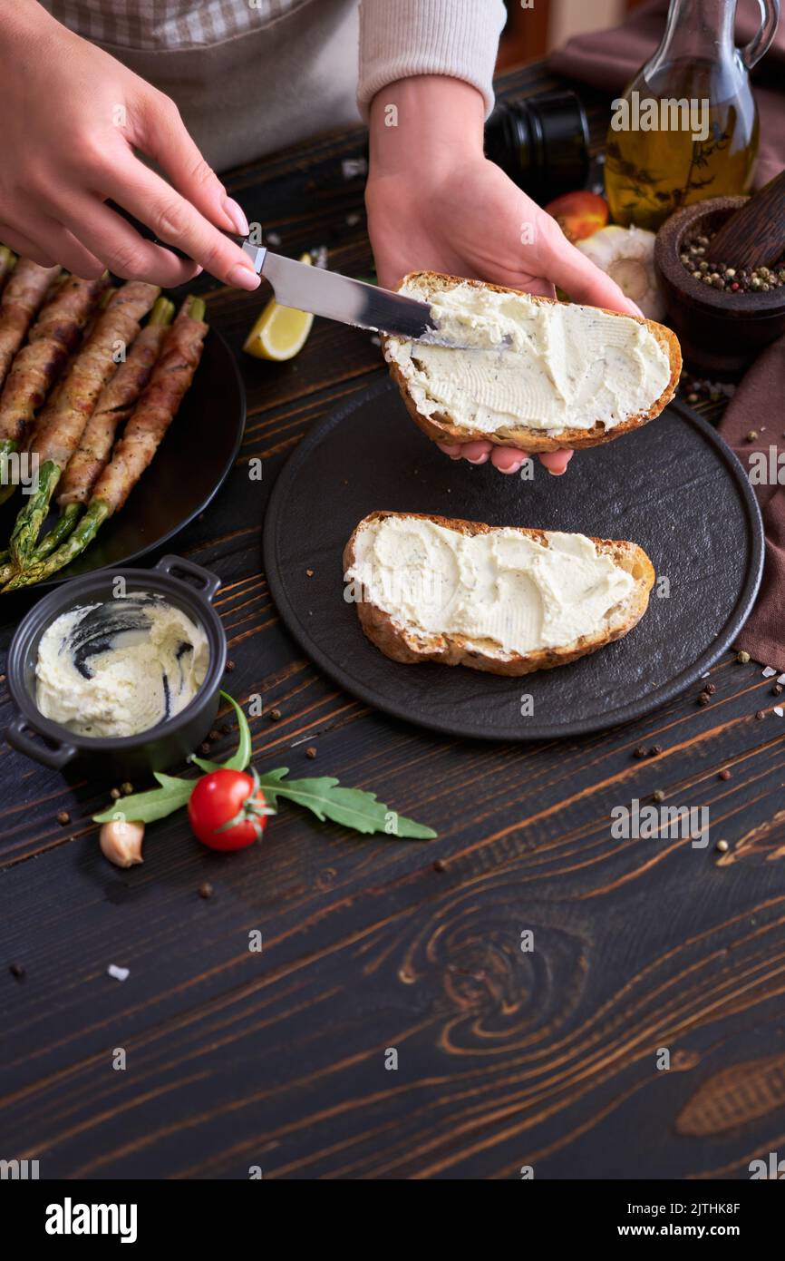 Making breakfast toasts woman smearing cream cheese on a grilled