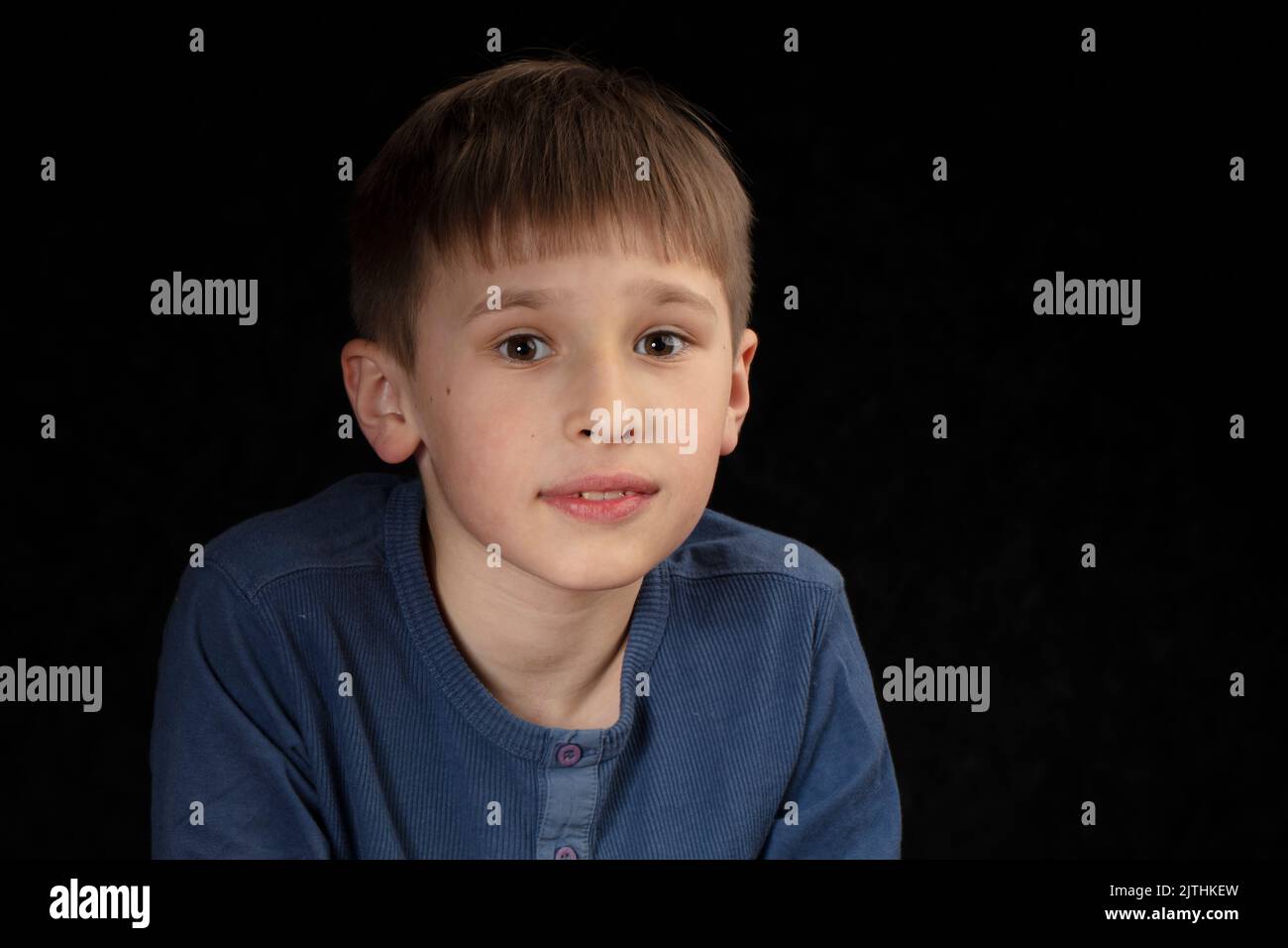 Portrait of a tenyearold boy on a dark background. The child looks