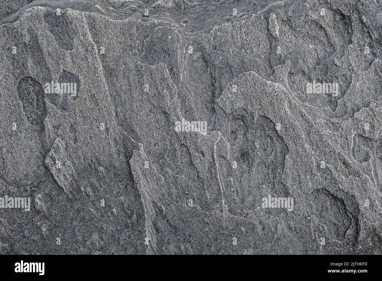 Close-up of a strange and beautiful rock surface, front view. Abstract full frame natural textured background in black and white. Stock Photo