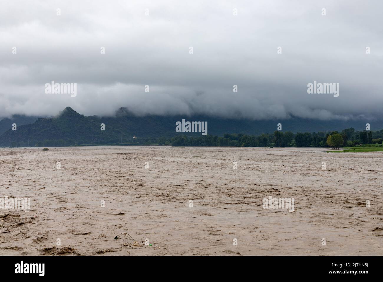 Heavy flood in the valley wash away crops and fields nearby the river bank Stock Photo