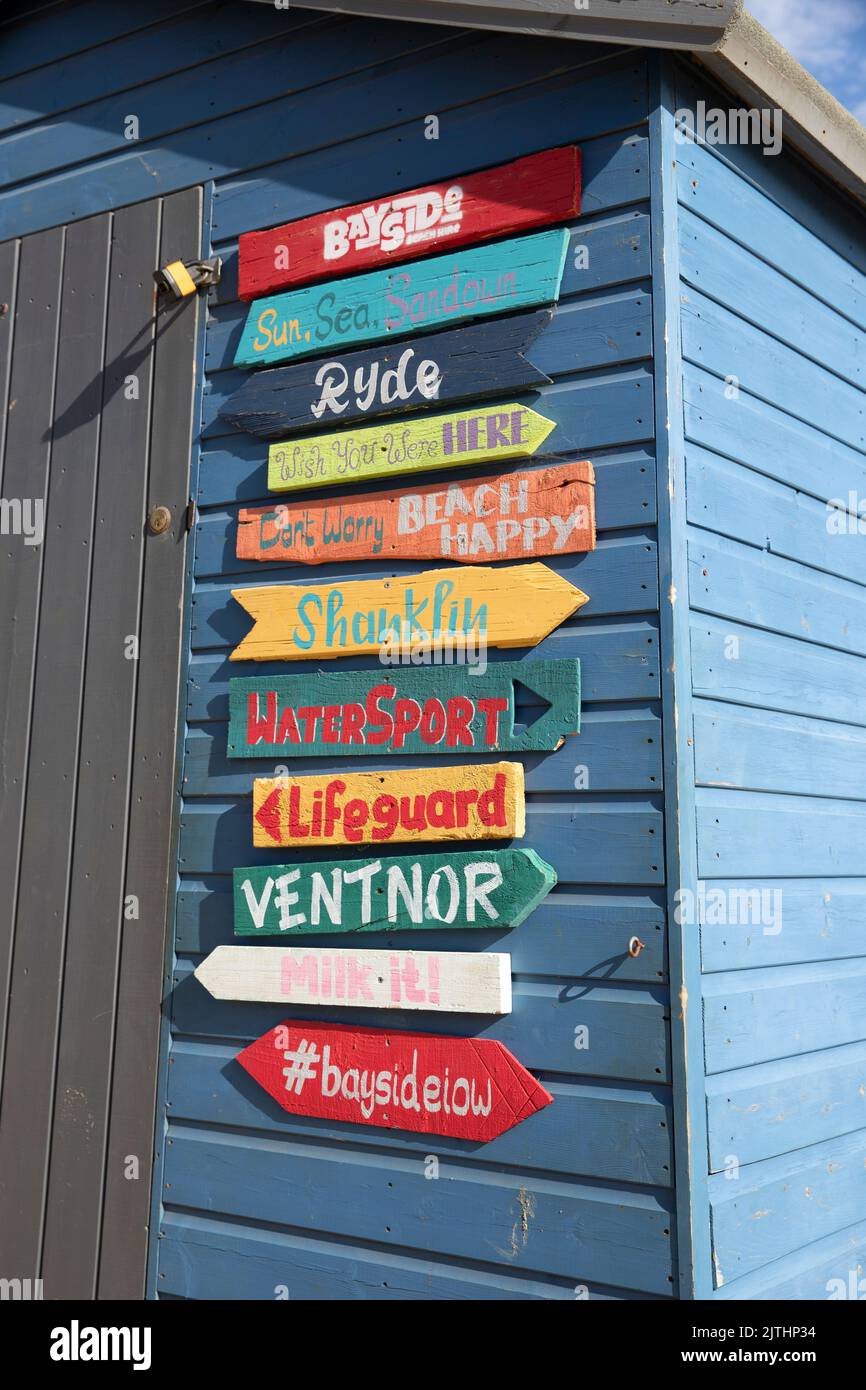 Multi-coloured arrow signs on a blue beach hut in Sandown, Isle of ...