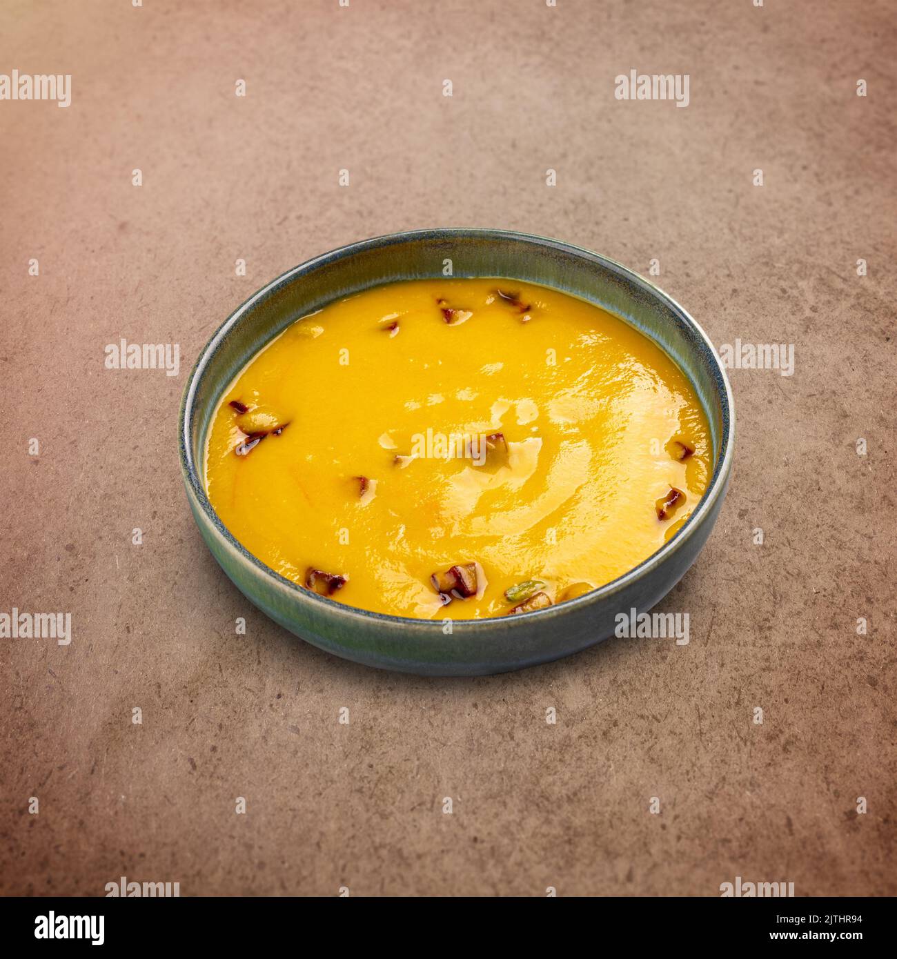 Bowl of tasty carrot cream soup on brown background Stock Photo