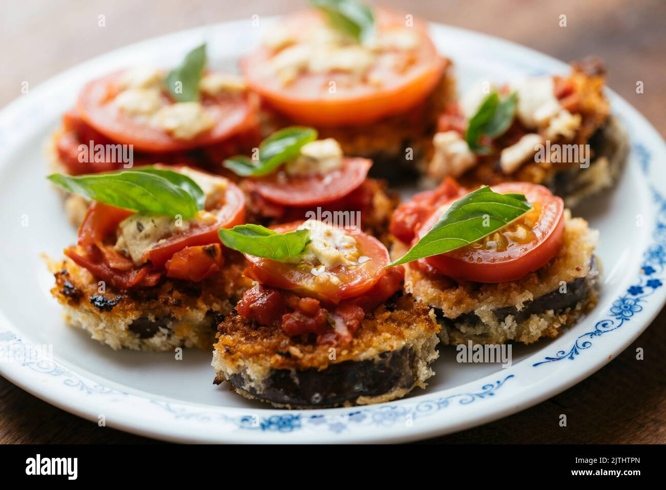 Breaded Eggplant Stacks with Tomato Sauce, Tomato Slice and Vegan Feta Stock Photo