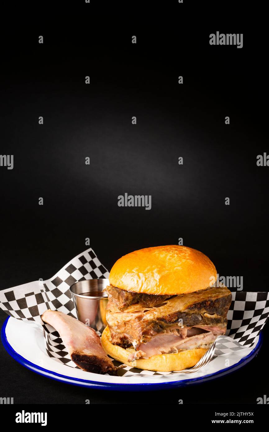 Beef rib burger and it's bone on a white plate over a black background Stock Photo
