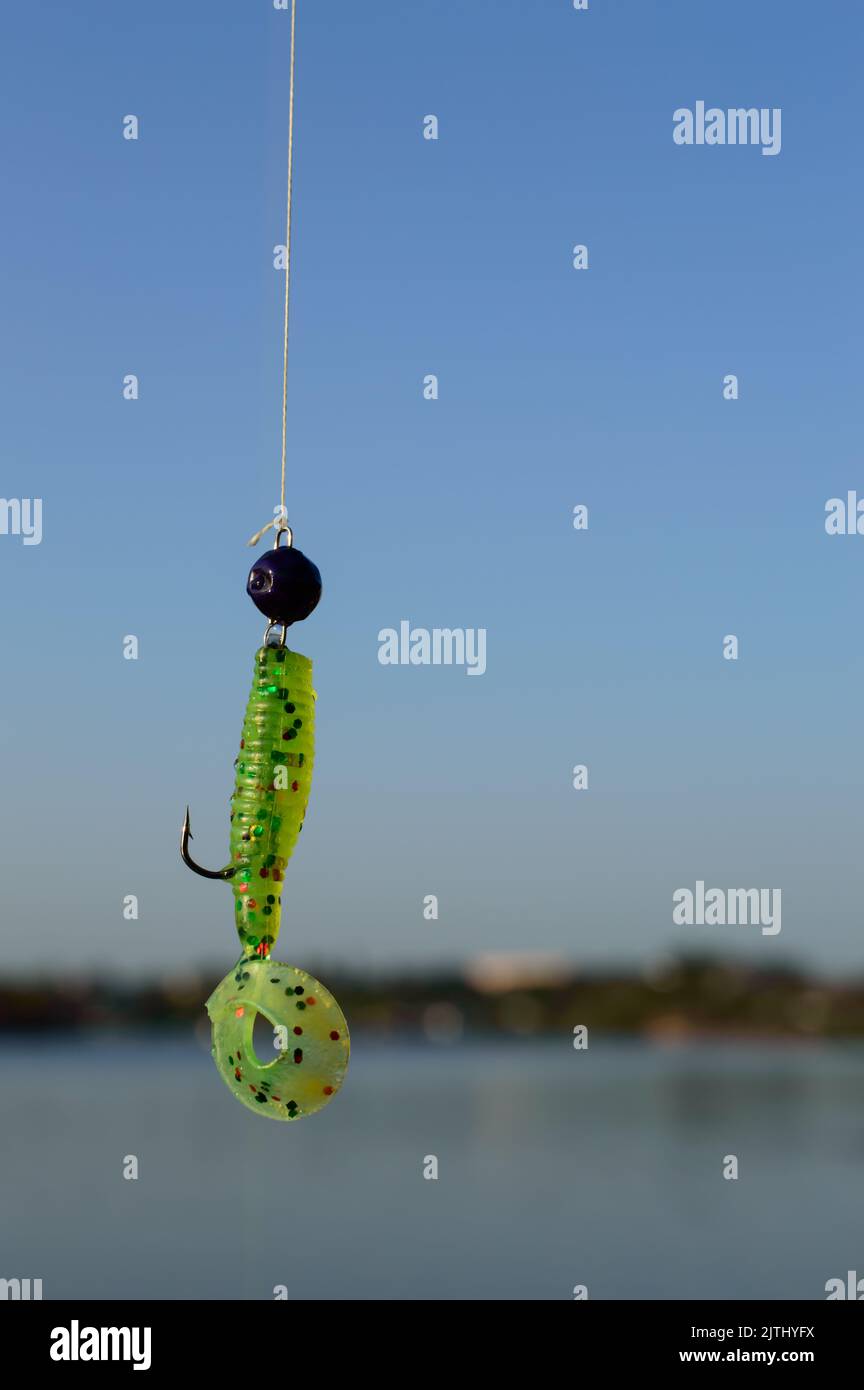 Green silicon fishing lure with a river on a background. Stock Photo