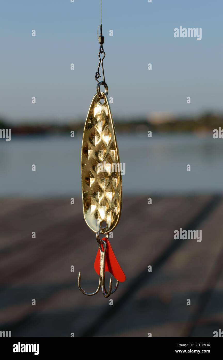Brass fishing lure with the river on a background. Stock Photo