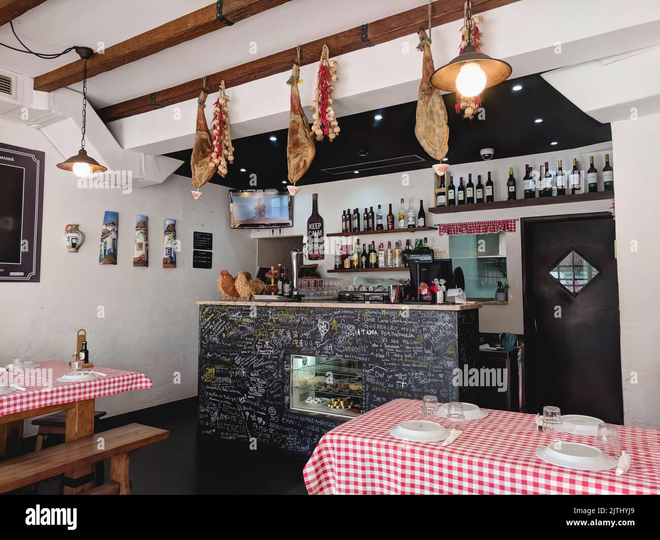 Bar in a restaurant in Vilamoura, Portugal with bottles of wine and hams hanging from the ceiling. Stock Photo