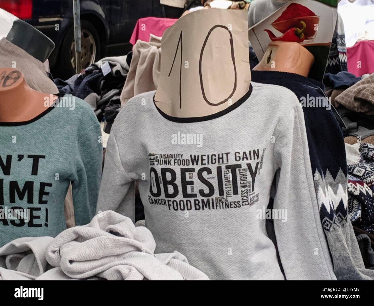 Sweatshirt for sale in a shop with some inappropriate words relating to food: obesity, disability, junk food, weight gain, cancer, BMI, fitness, excess weight, type 2 diabetes, genetic, fat mass Stock Photo