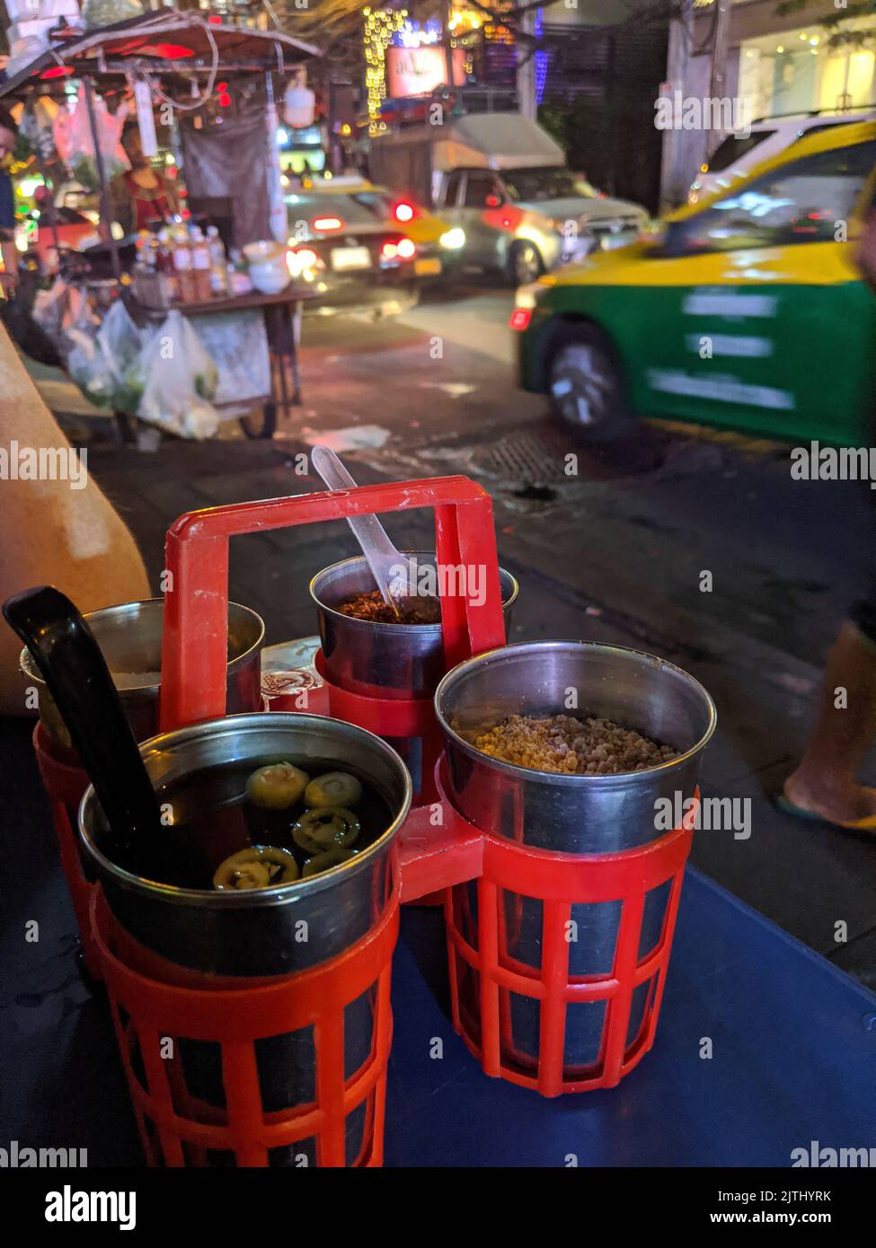 Condiments on a table on a footpath of a street food restaurant, Bangkok, Thailand Stock Photo