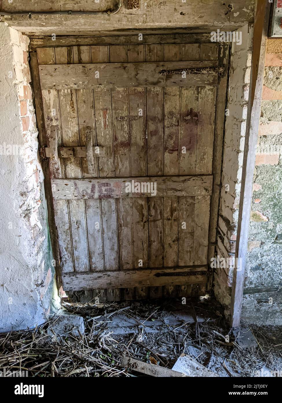 Wooden door with handmade latch inside a very old farm barn building. Stock Photo