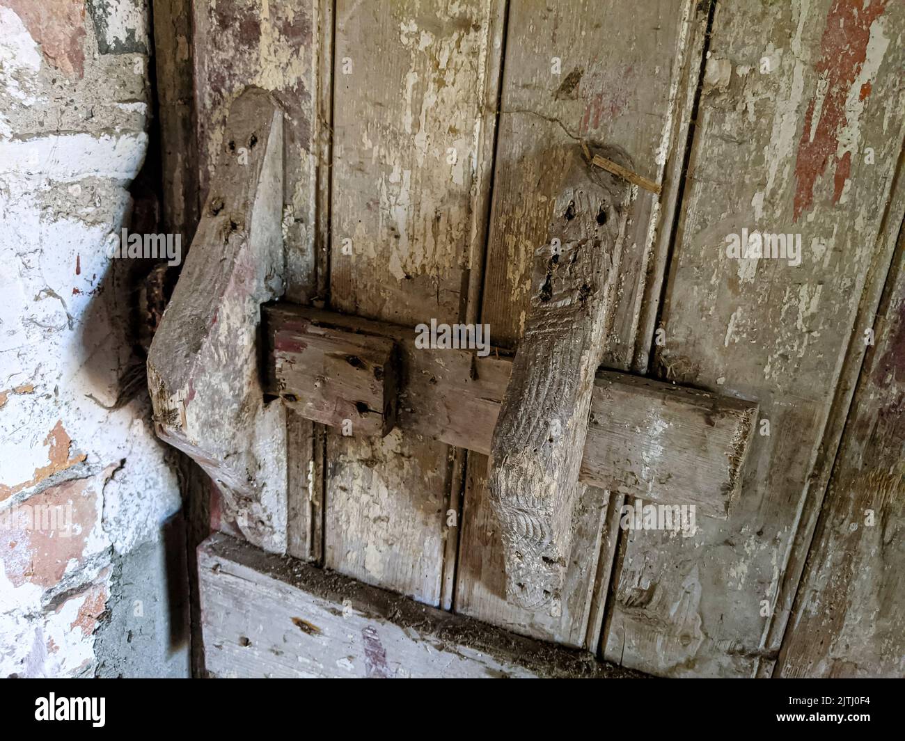 Wooden door with handmade latch inside a very old farm barn building. Stock Photo