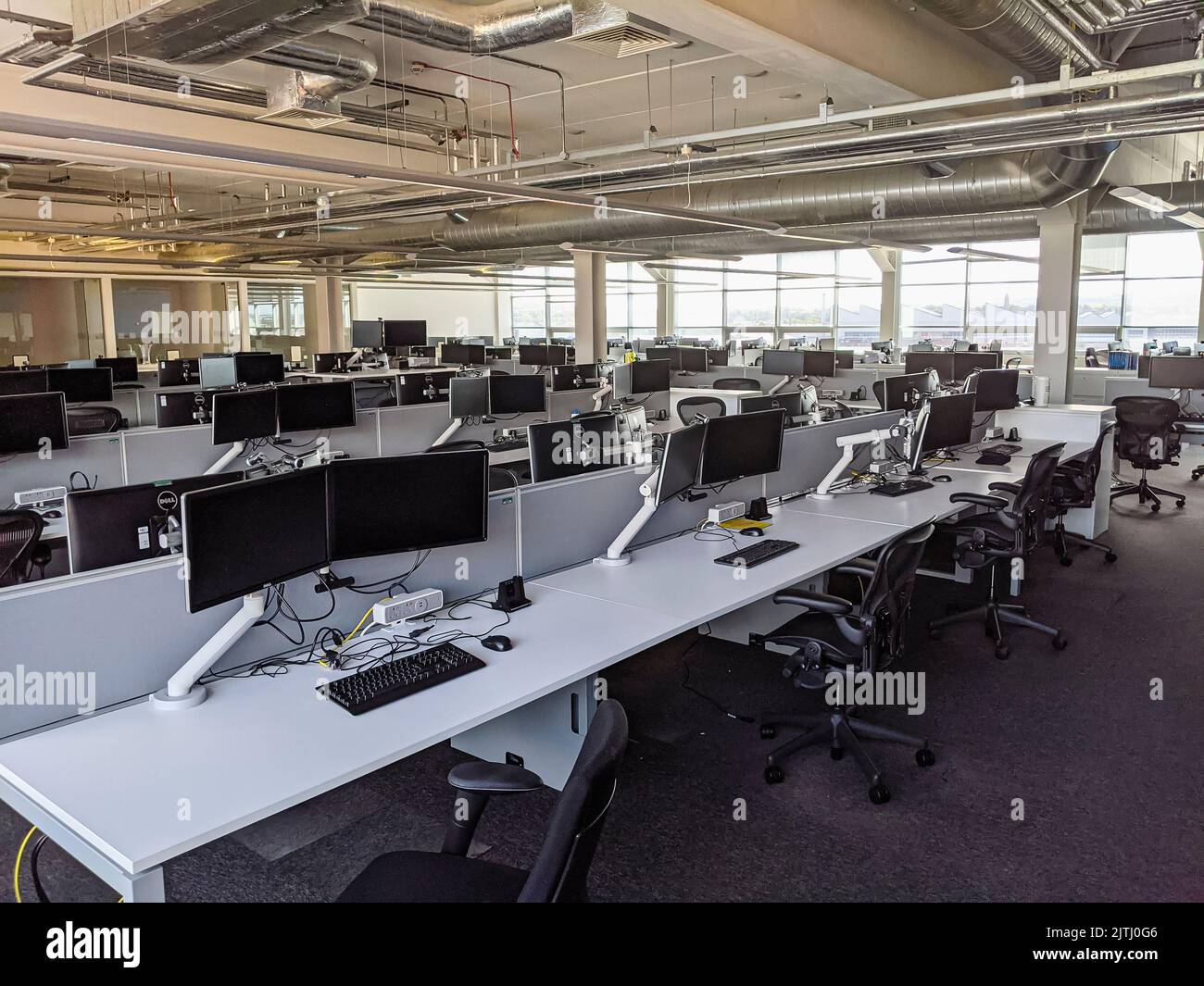 Empty office with desks, computer monitors and chairs set up for hot-desking. Stock Photo
