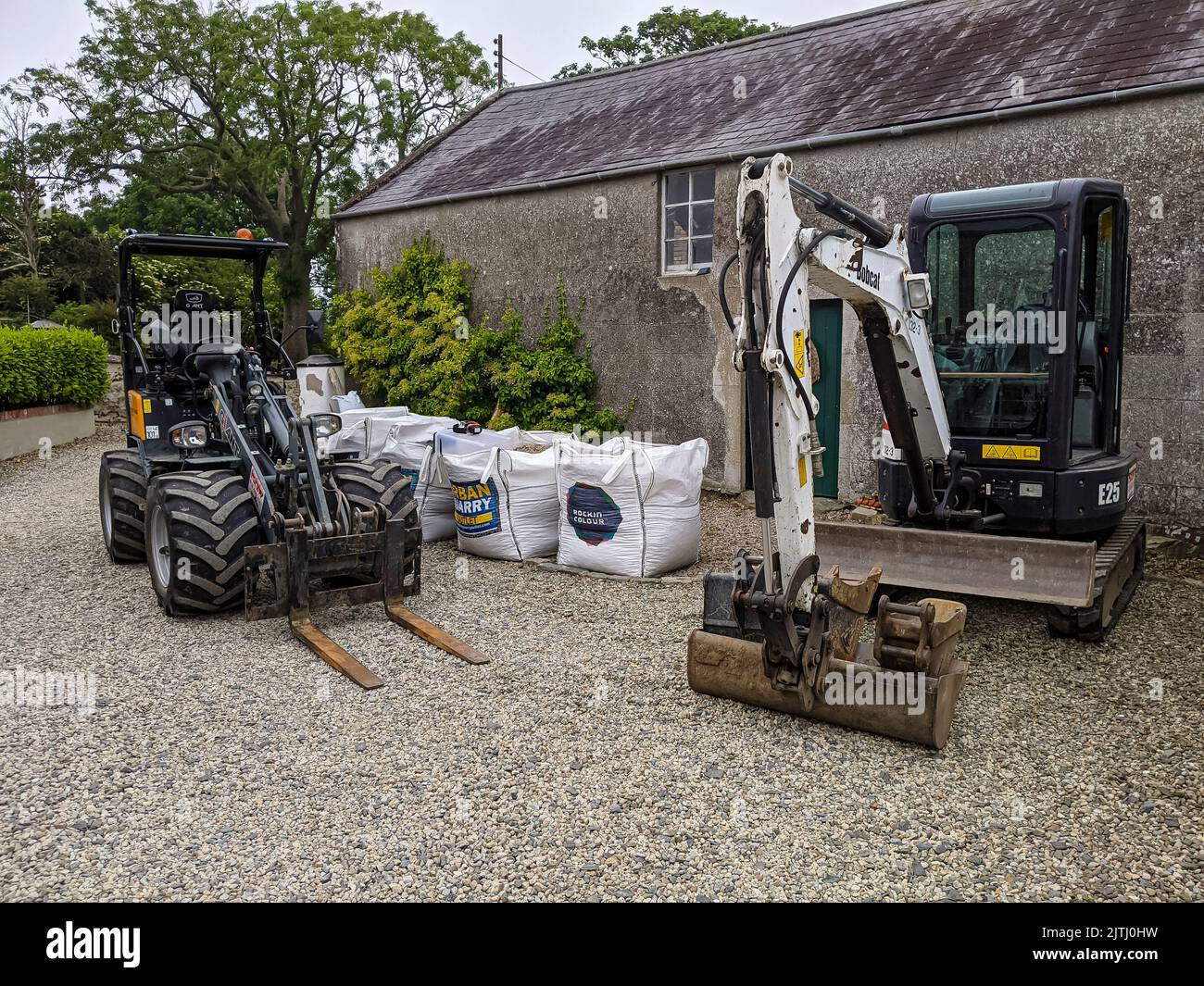 Giant forklift and 2.5 tonne Bobcat excavator on a gravel driveway