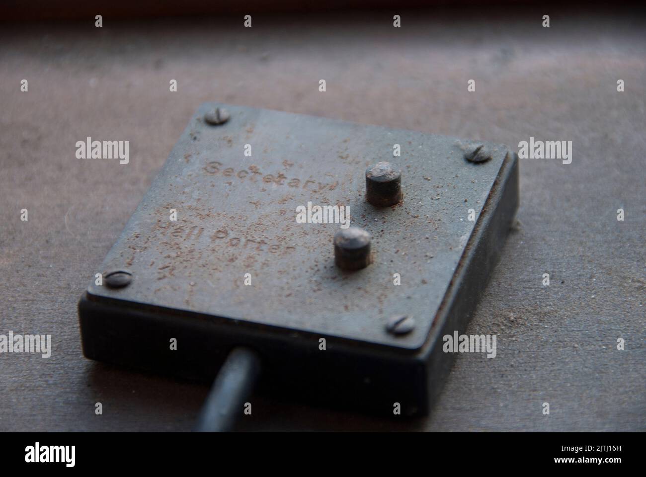 Rusty metal box with flying lead and buttons for 'Secretary' and 'Hall Porter' in an abandoned office Stock Photo