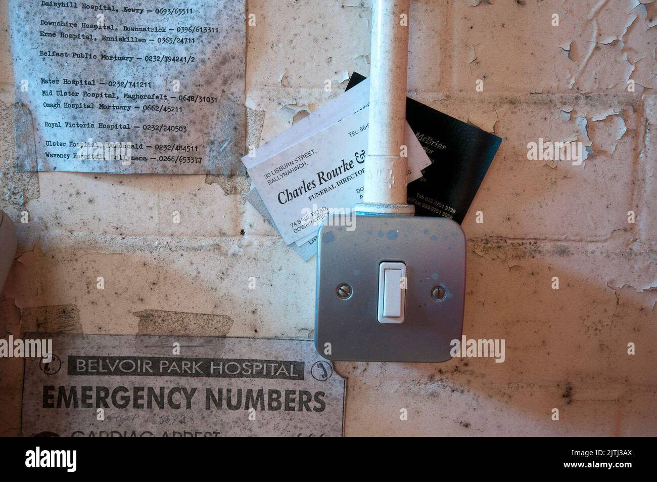 Emergency telephone numbers on the wall in a mortuary morgue of an abandoned hospital. Stock Photo