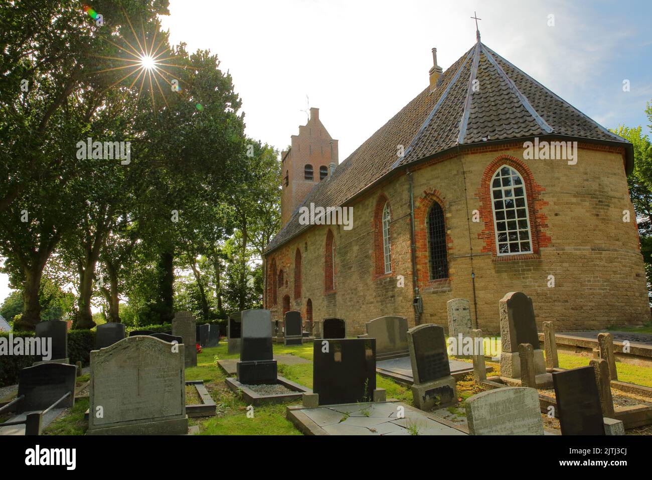 The Reformed Church (Hervormde Kerk), located on the mound of Hogebeintum, Friesland, Netherlands, with tombs in the foreground Stock Photo