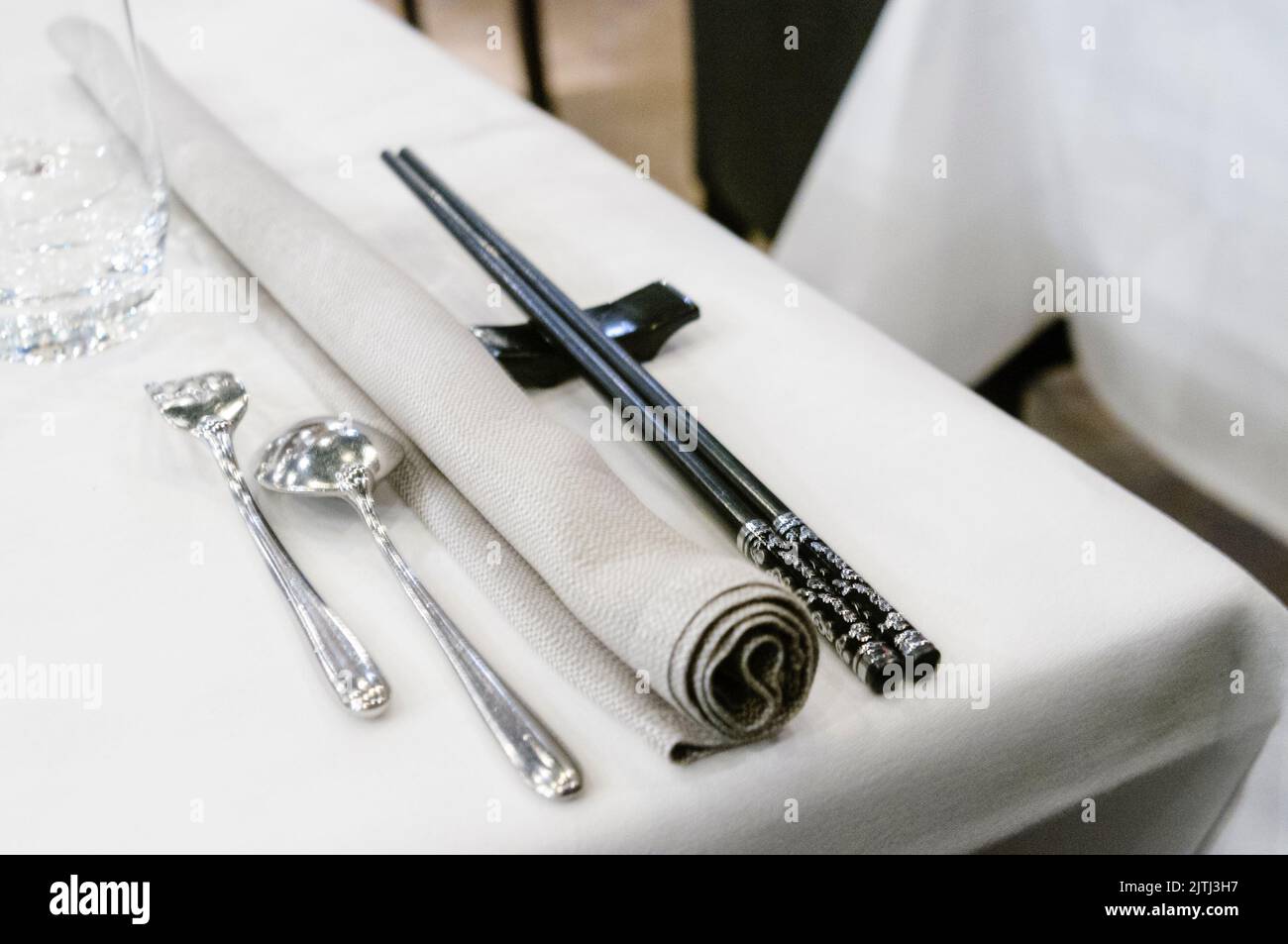 Chopsticks beside western silverware cutlery in an upmarket restaurant Stock Photo