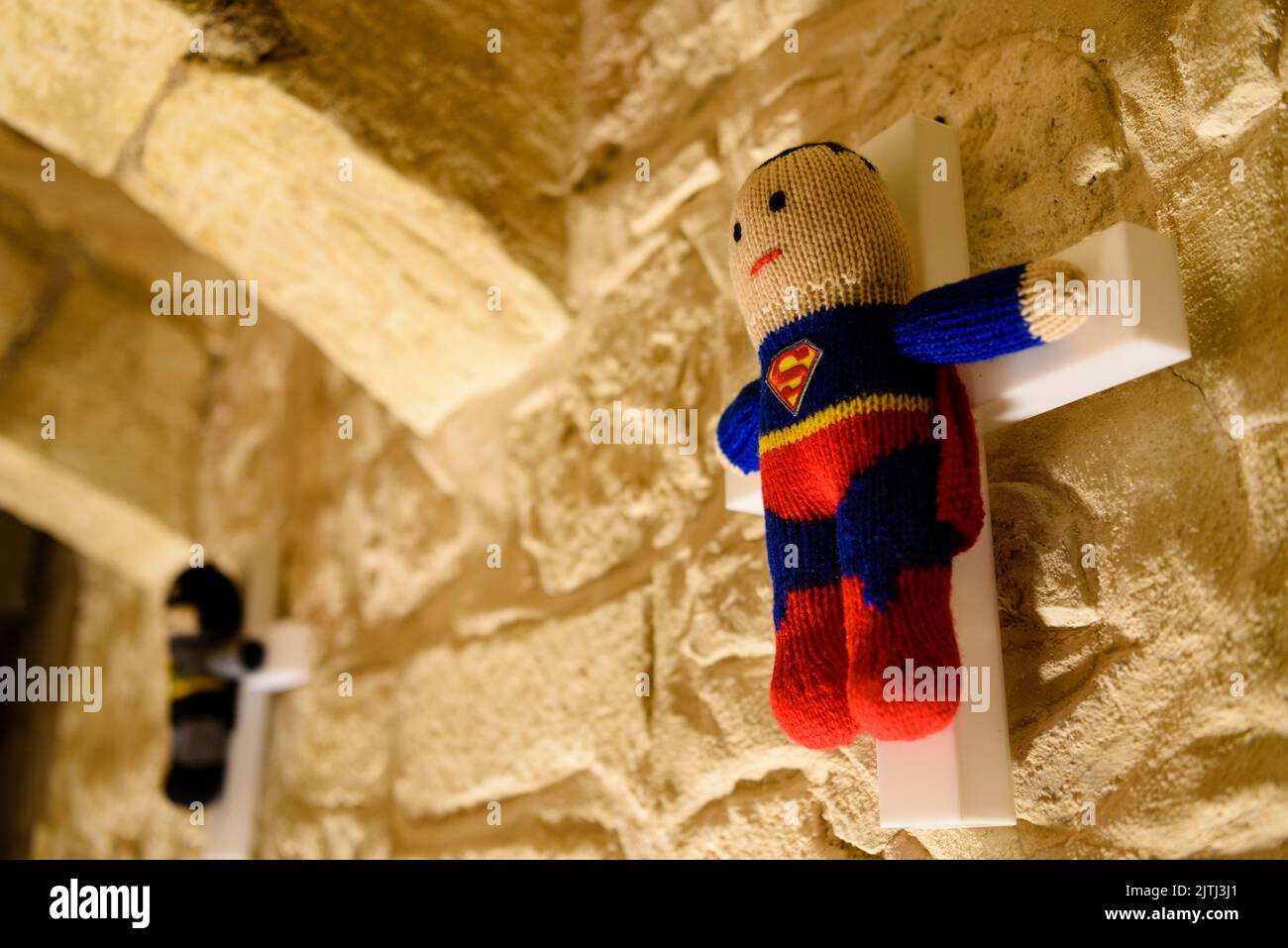 Knitted Superman and Batman on white wooden crosses as part of an art exhibition in Mdina, Malta. Stock Photo