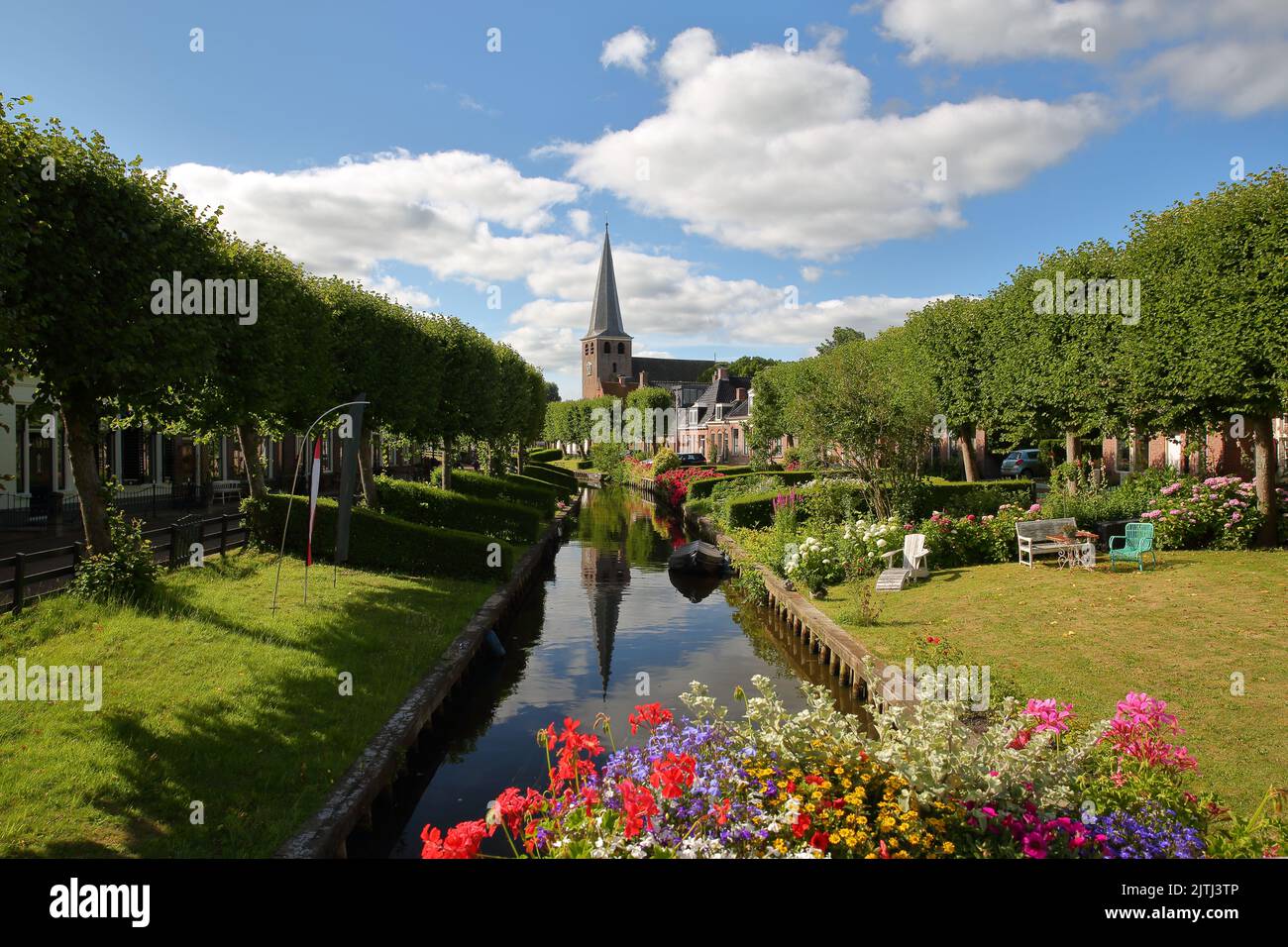 Eegracht canal surrounded by beautiful gardens in IJlst, Friesland, Netherlands, with Mauritiuskerk church in the background Stock Photo