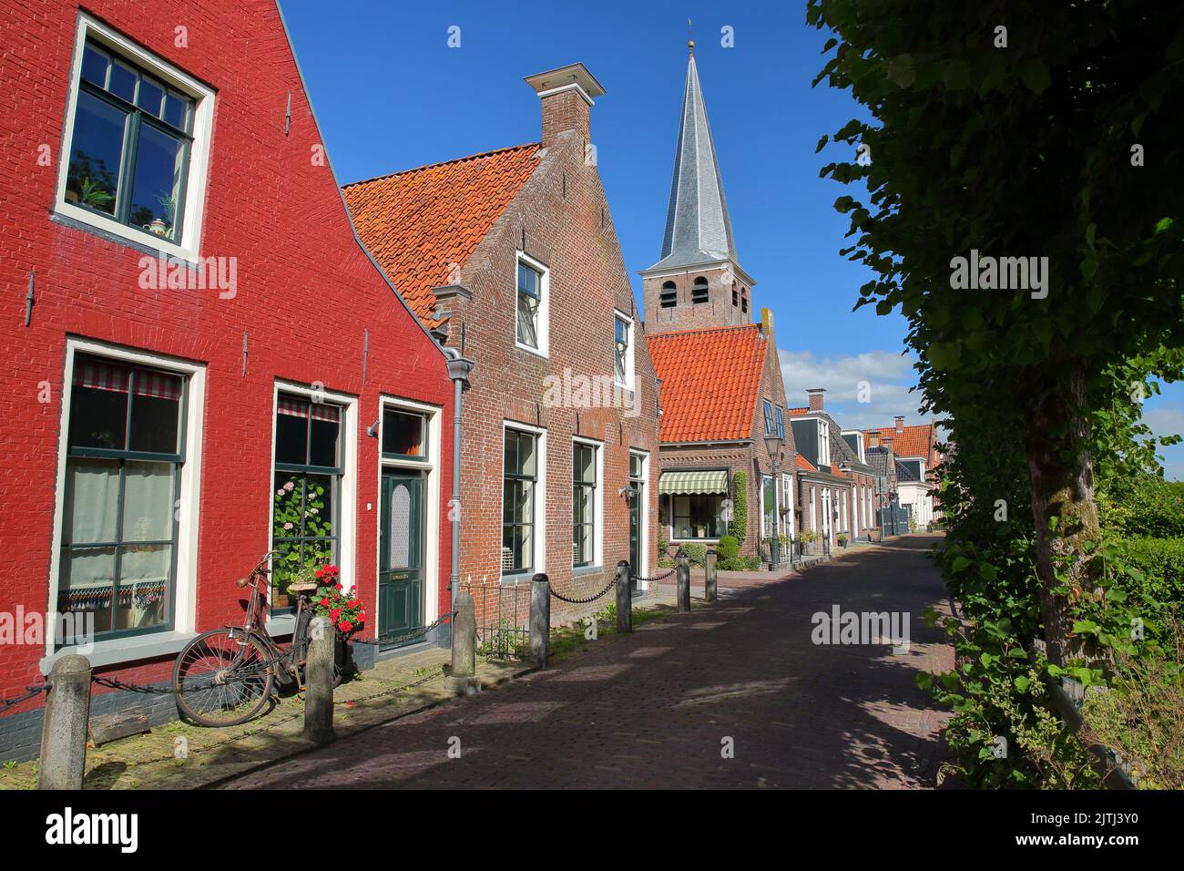 Colorful and historical houses in IJlst, Friesland, Netherlands, with the bell tower of Doopsgezinde kerk church in the background Stock Photo