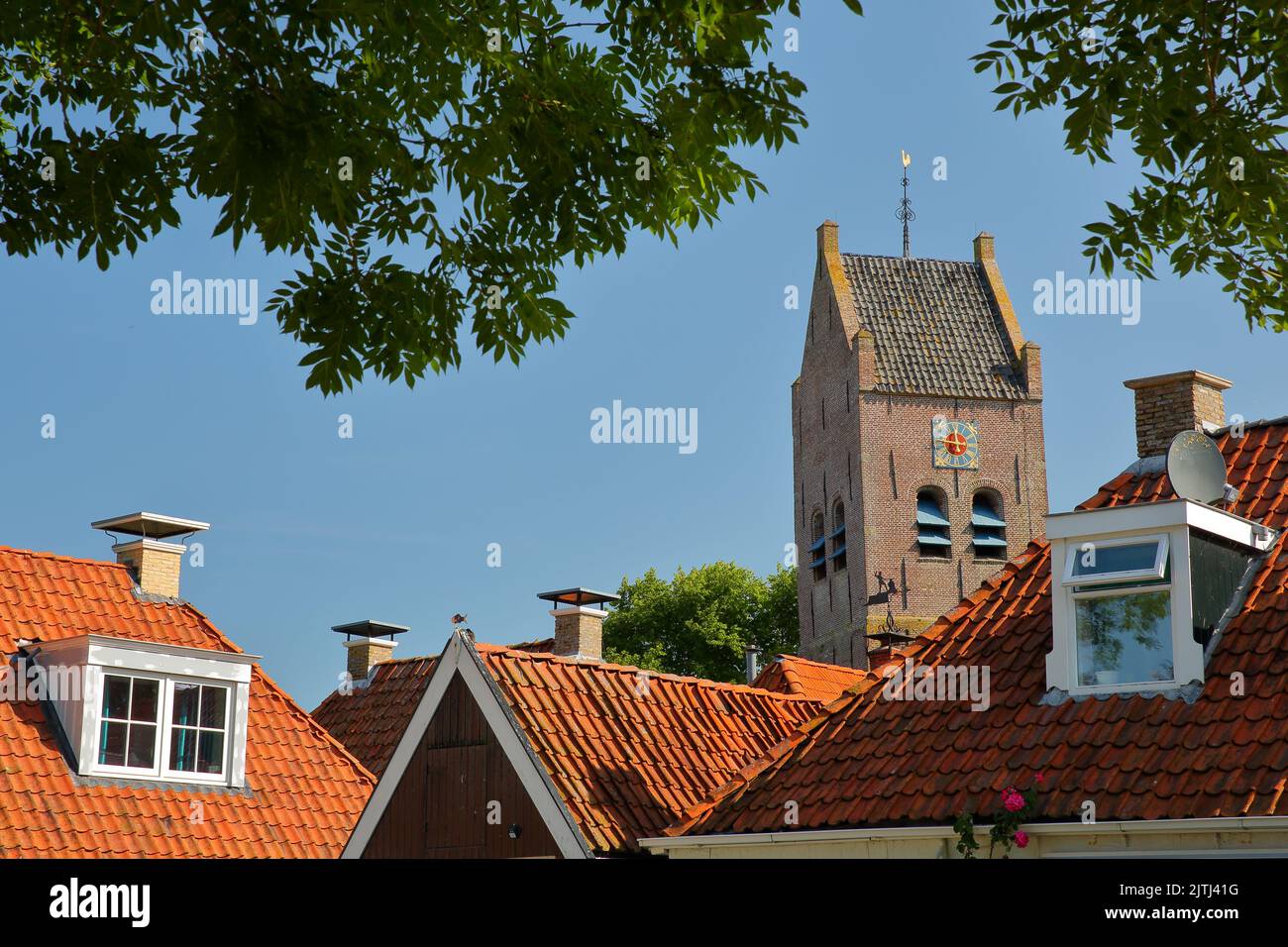 The roofs of historic houses and the massive bell tower of the Reformed Church (Hervormde Kerk) in Alligawier, Friesland, Netherlands Stock Photo