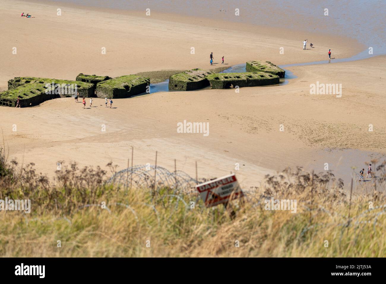 Tourists exploring the remains of the Mulberry harbour on the beach at Arromanches-les-Bains Stock Photo