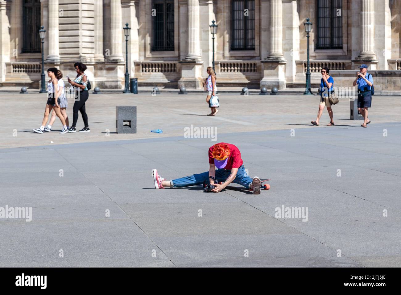 PARIS, FRANCE - AUGUST 30, 2019: An unidentified photographer is doing a stretch in the middle of the square in search of an unusual angle. Stock Photo