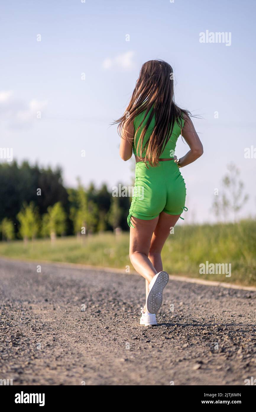 The vertical view of a female from behind running in the park while