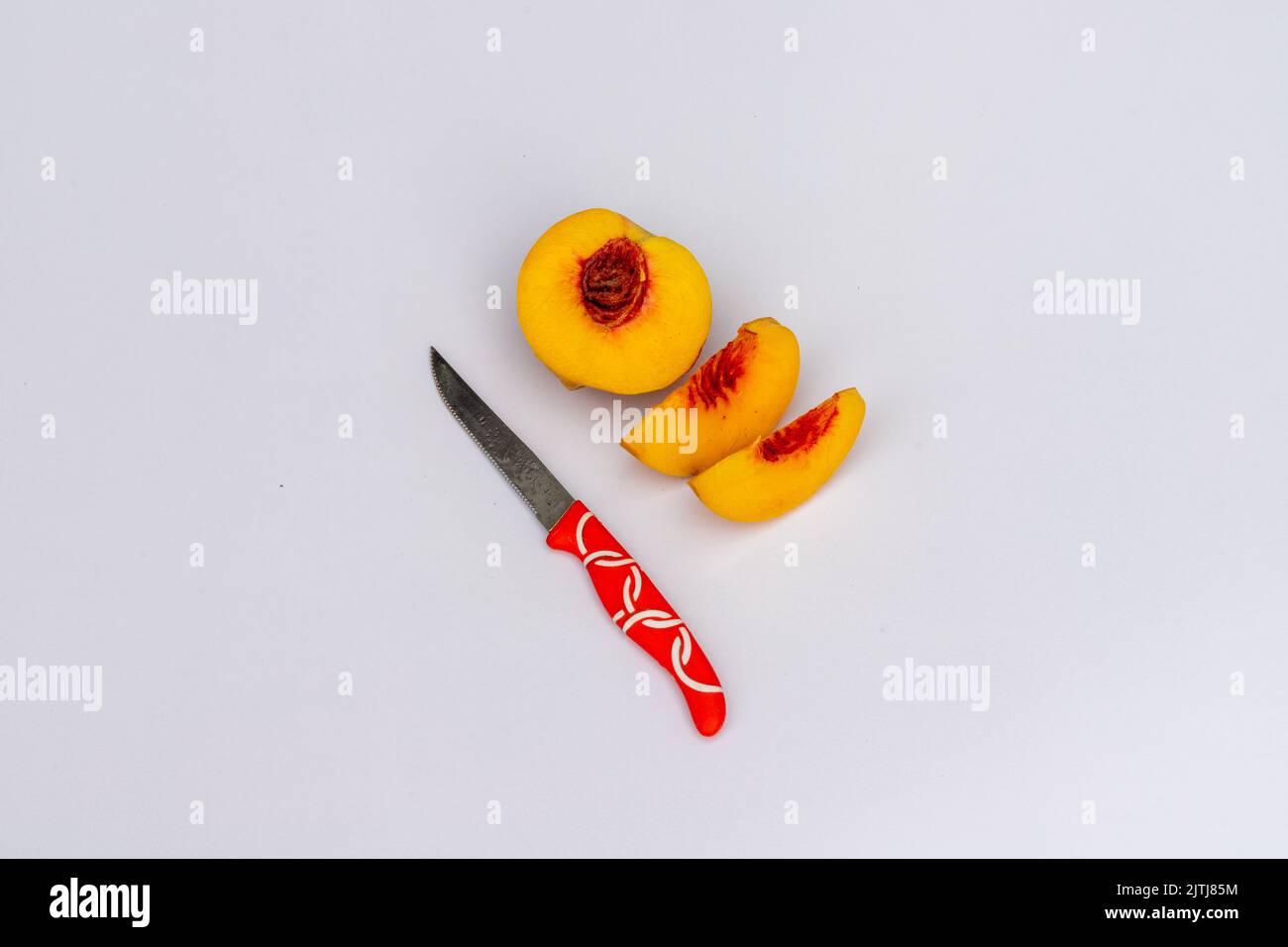 Peach fruit sliced with knife on white isolated background Stock Photo
